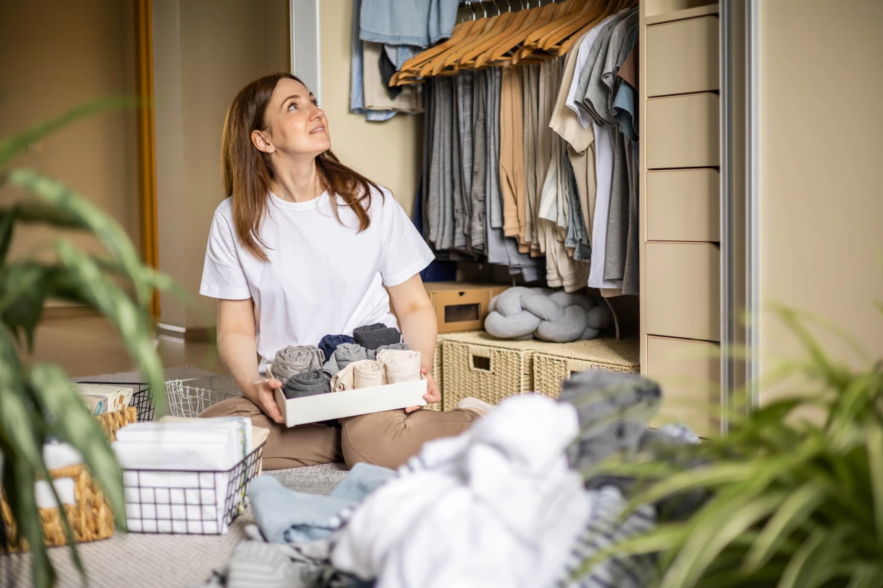 Sortieren Sie die Kleidung mit System und Ordnung zurück in den Schrank. Frau sortiert ihre Kleidung mit einem Ordnung und System zurück in den Kleiderschrank