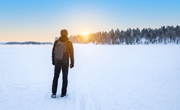 Richtig angezogen bis in die Abendstunden sind Winterwanderungen kein Problem Wanderer im Schnee, blickt beim Sonnenuntergang Richtugn Wald