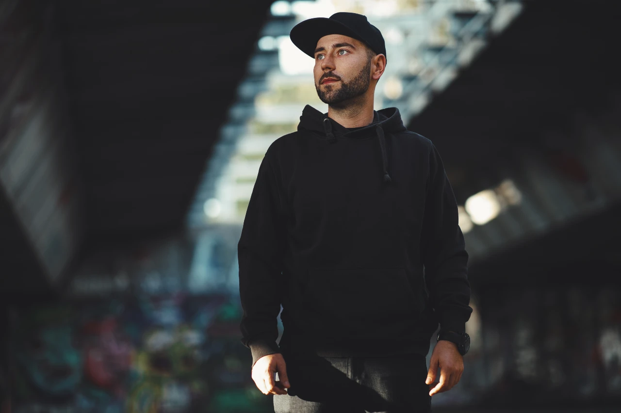 Sportlich in Schwarz: Hoodie, Cap und lässige Jeans machen das All-Black-Outfit zum coolen Streetstyle. Mann trägt chwarzen Hoodie, Cap und Jeans als Ton-in-Ton-Look