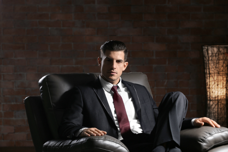 мужчина в классическом костюме сидит в кресле