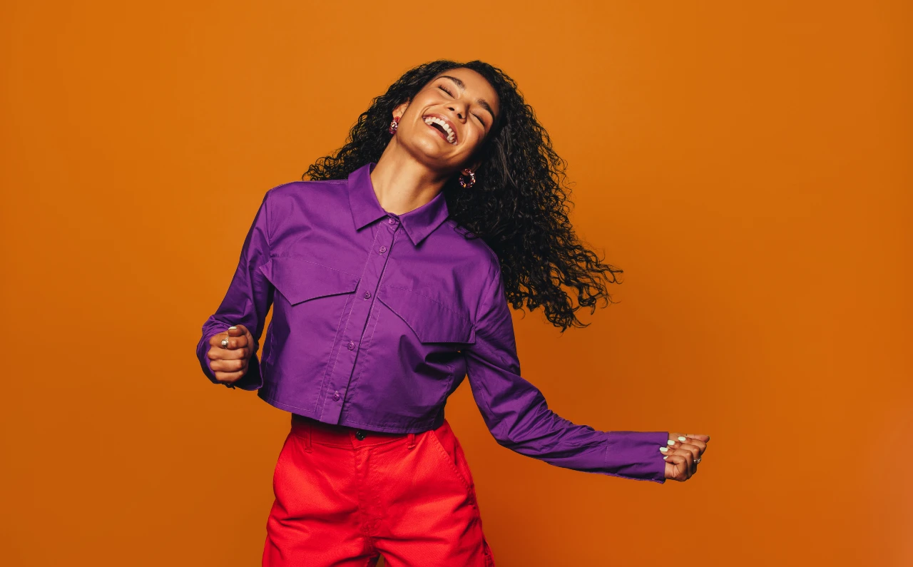 Frau trägt eine violette Bluse zu einer roten Hose als Colour Blocking