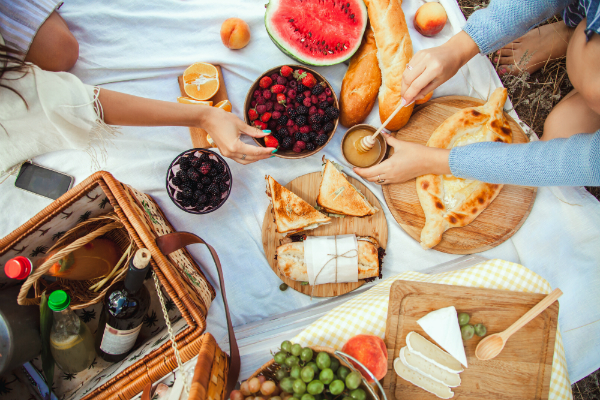 Picknick mit Obst, Kaese, Toast, Honig, Wein mit einem Weidenkorb und eine Decke