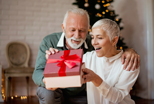 Aelterer Mann gibt seiner Frau ein Weihnachtsgeschenk