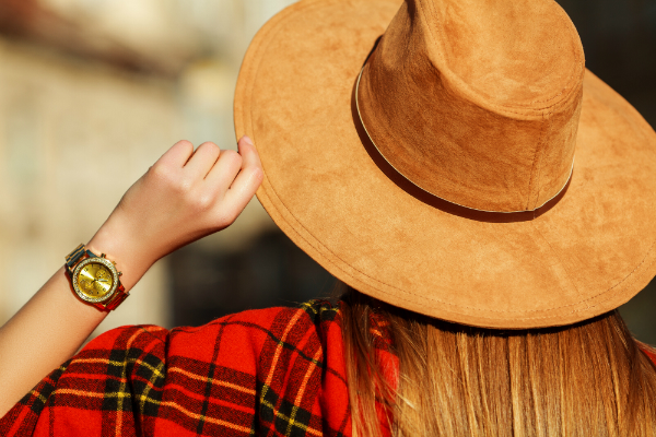 Frau mit hellbraunem Hut aus Wildleder und goldener Armbanduhr