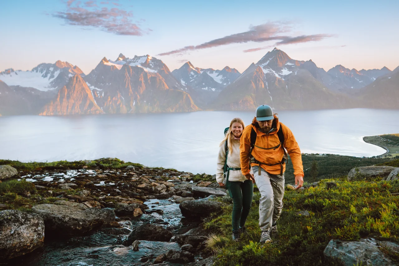 Mann und Frau wandern in passender Wanderbekleidung einen Berg hoch