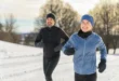 Mann und Frau joggen im Schnee mit passender Laufbekleidung im Winter
