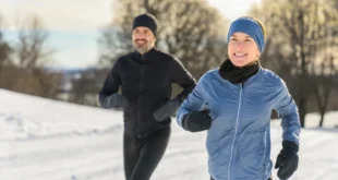 Mann und Frau joggen im Schnee mit passender Laufbekleidung im Winter
