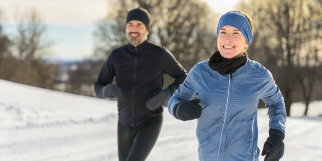 Mann und Frau joggen im Schnee mit passender Laufbekleidung im Winter