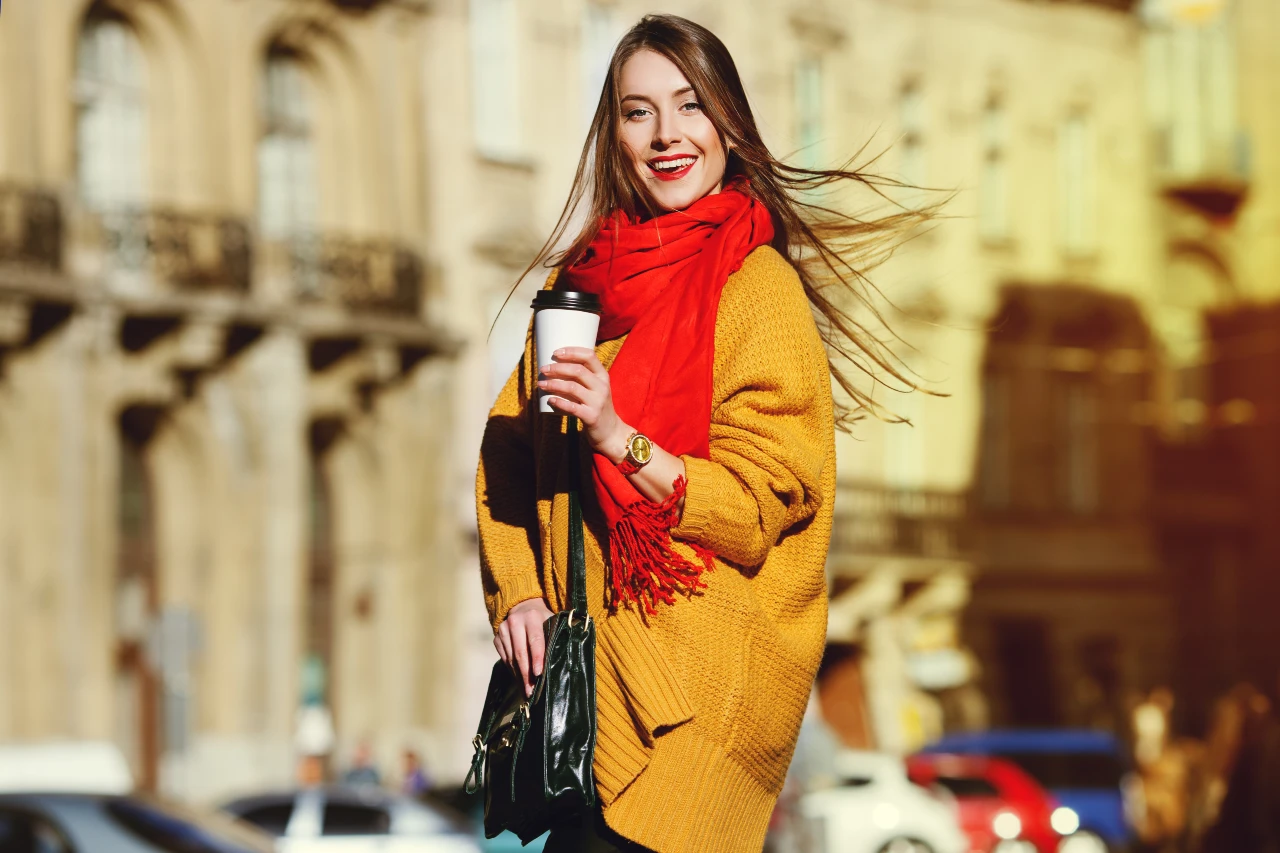 Macht gute Laune! Ein Schal in Tomatenrot ist ein toller Farbtupfer im Herbst. Frau trägt winterlichen Schal in Rot mit einem gestrickten Cardigan in Senfgelb