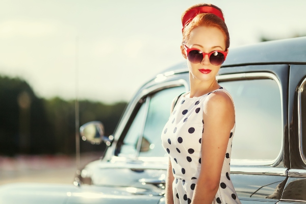 Frau im Retro-Stil und Polka Dots neben einem Oldtimer