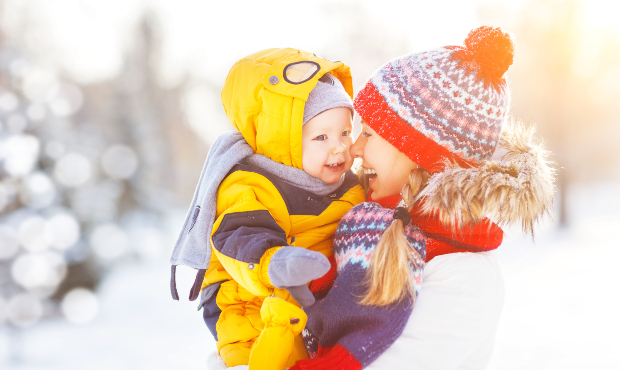 Fröhliche Mutter mit fröhlichem Kleinkind in Winterkleidung