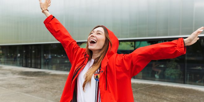 Junge Frau lächelnd im Regen - Regenfeste Kleidung modisch kombiniert