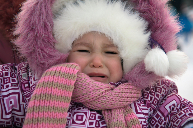 Kleines Mädchen in pinker Kleidung weint - die Babykleidung im Winter könnte zu warm oder zu kalt sein