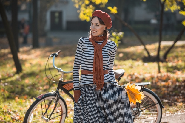 Dame mit gestreiftem Oberteil und Rock mit einem Fahrrad