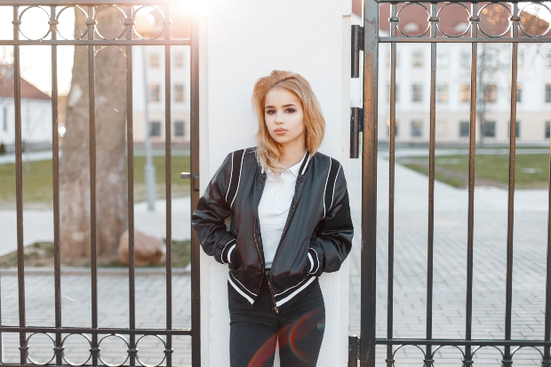 Studentin mit einer Blousonjacke vor einem Tor