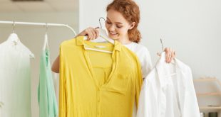 Junge Frau wählt unterschiedliche Basic-Kleidungsstücke aus, die an einem Kleiderständer hängen