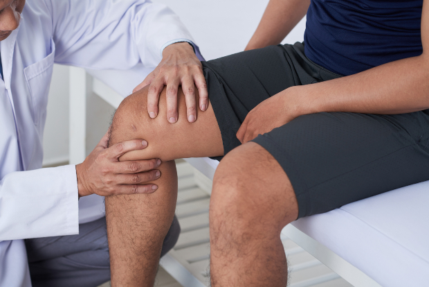 Knie eines Mannes wird vom Arzt untersucht - Einsatz von Arbeitsknieschonern hilft