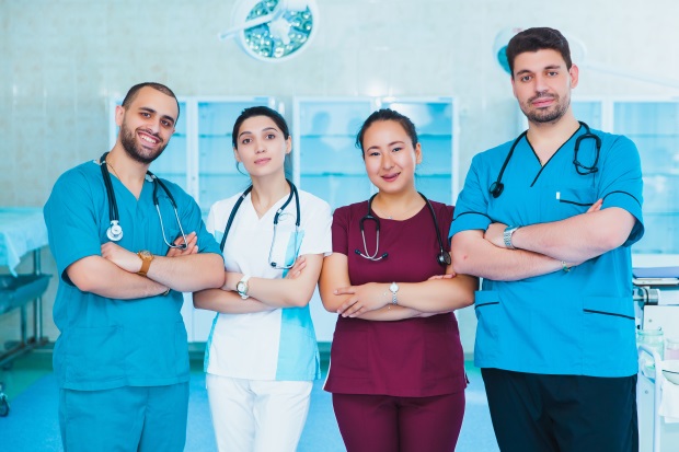 Eine Gruppe von Ärzten und Krankenpflegern in weißen, roten und hellblauen Kasacks 