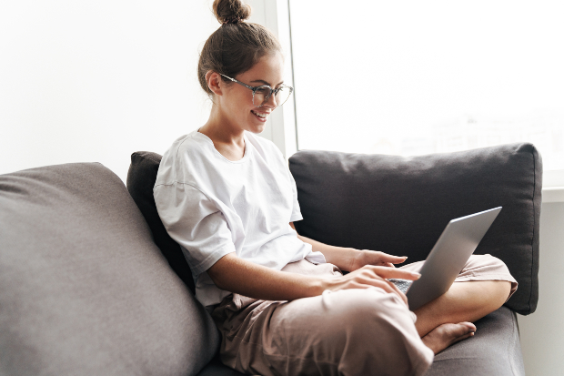Junge Frau auf der Couch mit Laptop - Leichtes Outfit für zuhause