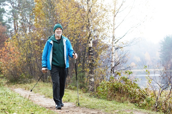 Ein älterer Herr betreibt bei kühler Witterung Nordic-Walking - Walking Outfit