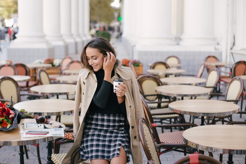 Frau mit kariertem Rock und Trenchcoat