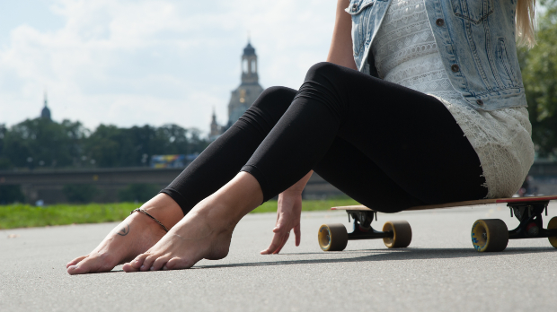 Eine Frau, die schwarze Leggings trägt, sitzt auf einem Skatboard Leggings kombinieren