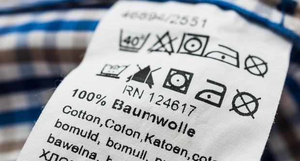 Ein Schild mit Pflege- und Waschhinweisen für ein T-Shirt auf dem „100% Baumwolle“ steht T-Shirt kaufen