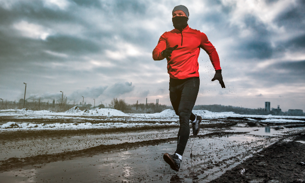 Gekleidet mit winterlicher Running-Bekleidung joggt ein Mann an einem kalten Tag