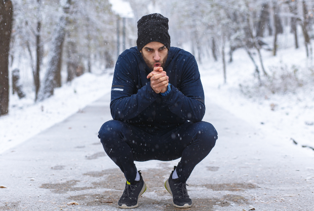 Ein Jogger, der an einem kalten Wintertag unterwegs ist, pustet in seine Hände, um sie zu wärmen