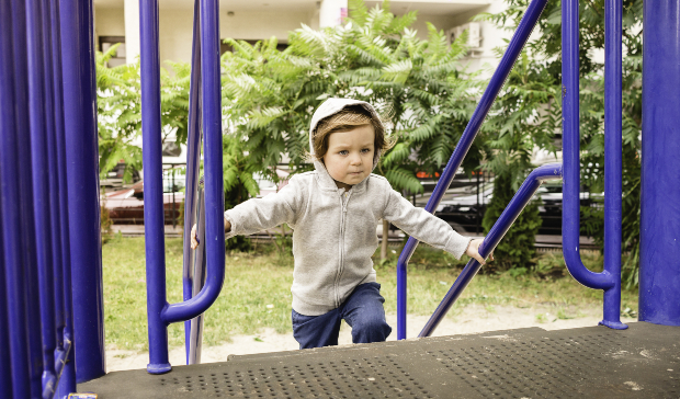 Kind mit Hoodie spielt auf Treppe - Kindergartenkleidung