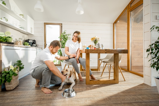 Junges Ehepaar in der Küche in Freizeitkleidung mit Hund