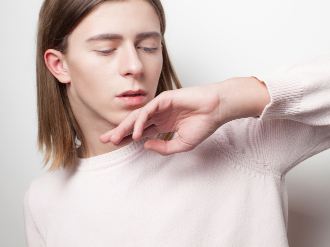 Junger Mann mit längeren Haaren in rosé-farbenem Pullover