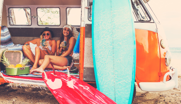 2 junge Frauen im VW Bulli am Strand - Surfer Style