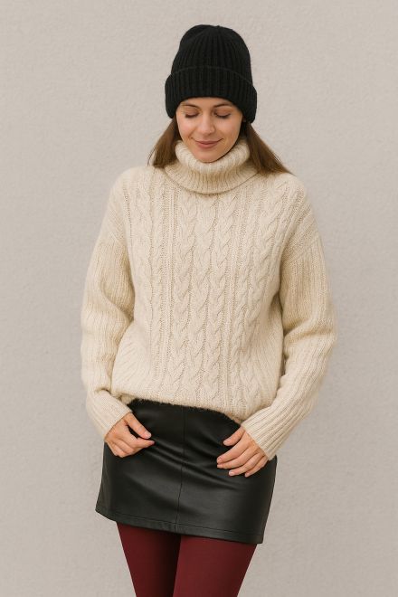 Frau im Winteroutfit mit cremefarbenem Zopfmuster-Pullover, schwarzem Minirock, bordeauxfarbenen Strumpfhosen und schwarzer Mütze