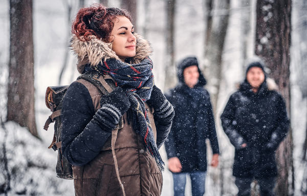 Eine junge Frau mit Rucksack in einem winterlichen Wald