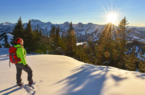Eine Frau steht auf einem verschneiten Berg und genießt den Ausblick