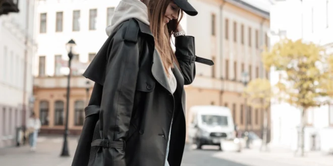 Frau trägt einen langen schwarzen Mantel, grauen Hoodie und schwarze Cap als klassischen Berlin Style