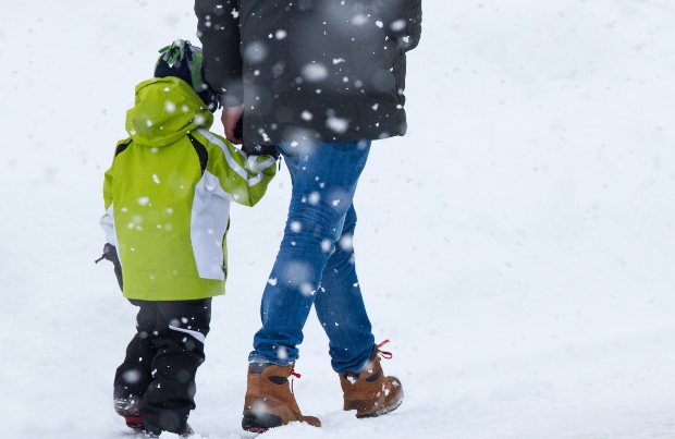 Mutter spaziert mit Kind durch den Schnee