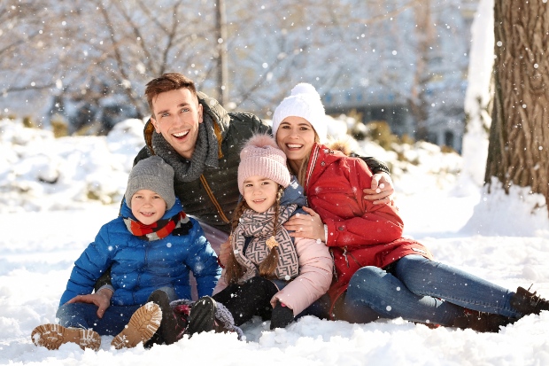 Junge Familie im Schnee - Kinderwinterjacken sollte man sorgältig aussuchen
