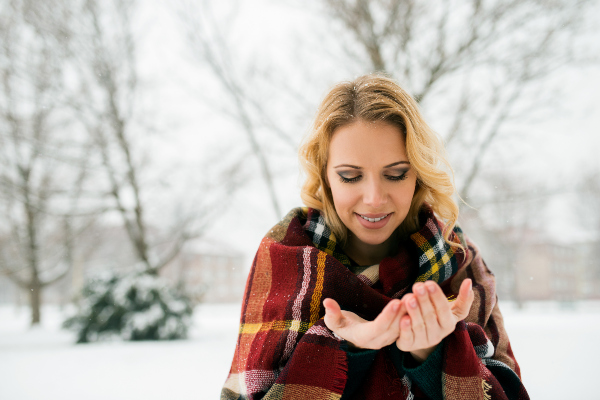 Eine junge Frau vor einer verschneiten Landschaft, sie trägt einen winterliche Mode mit Karomustern