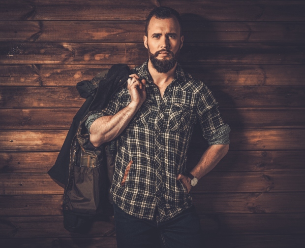 Mann vor Holzwand im Karohemd und Jacke - Lumberjack Style