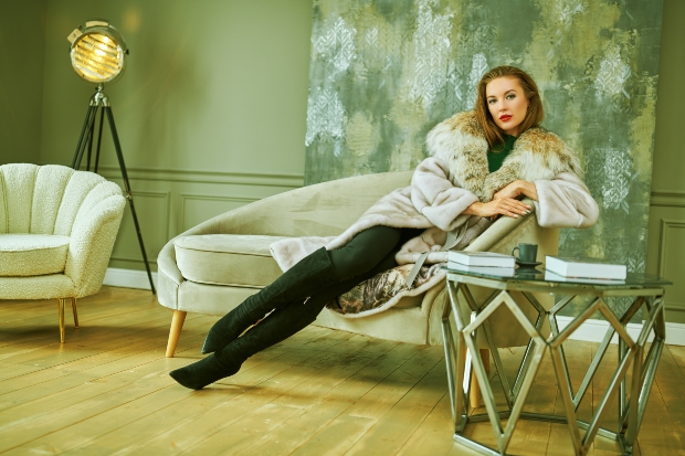 Frau mit Pelz und Overknees auf einem Sofa