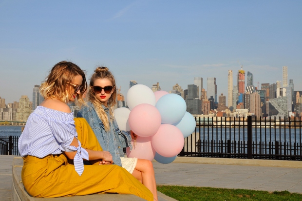 Zwei junge Frauen sitzen vor der New York Skyline - Kleidung in großen Größen