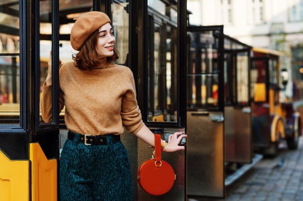 Eine Frau mit Strickhose und Rollkragen posiert vor einer urbanen Kulisse Strickhose