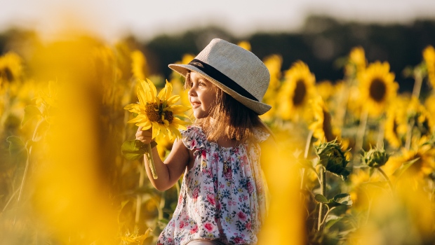 Kind mit Sommerkleid im Sonnenblumenfeld - Trends bei Kinderoutfits