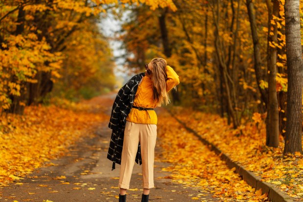 Vor einer herbstlichen Allee posiert eine Dame in Strickhose und Oversize Pullover Strickhose