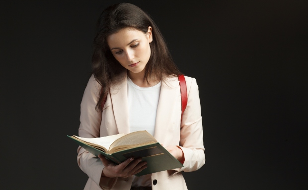 Junge Frau im Blazer mit Buch in der Hand