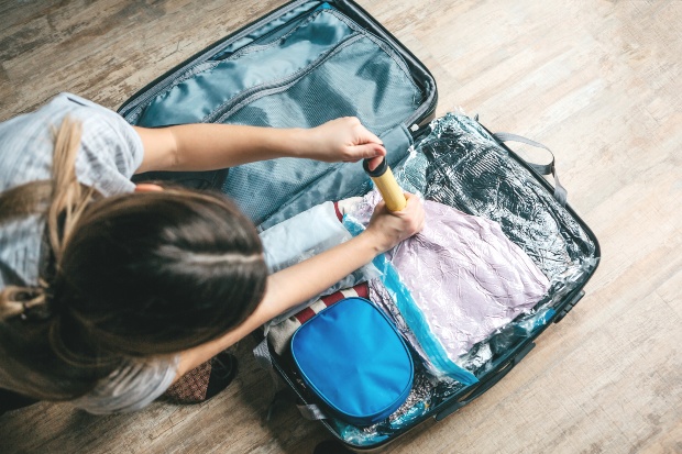 Junge Frau vakuumiert Kleidung im Reisekoffer