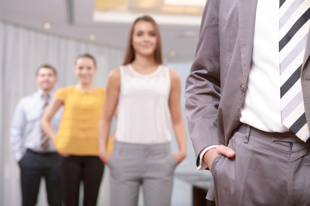 Vier Personen in unterschiedlichen Büro-Outfits stehen hintereinander.