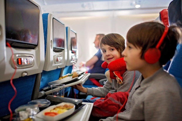 Kinder in einem Flugzeug nutzten die On Board Fernseher - Verreisen mit Kind